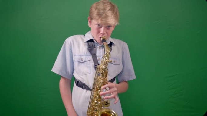 12岁的男孩正在工作室里演奏萨克斯管，背景是绿色色键。