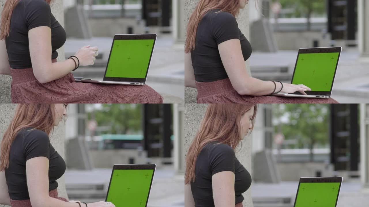 可爱的女人在户外用笔记本电脑。模拟绿屏。查看手机上的验证码，然后在internet上购买产品。在商务