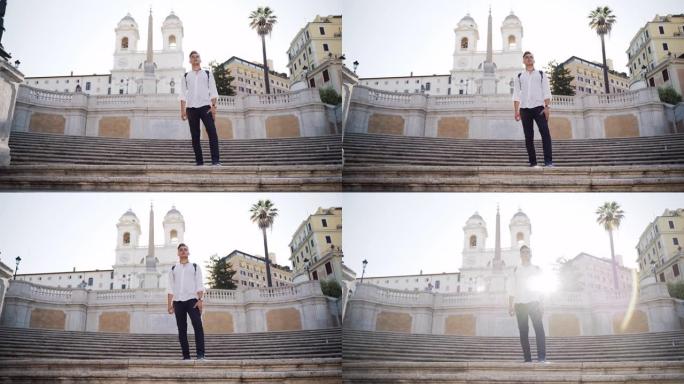穿着黑色帆布背包的英俊高挑年轻游客在罗马的楼梯上逗留。惊人的古代背景与日出背后的男人。早晨的意大利氛