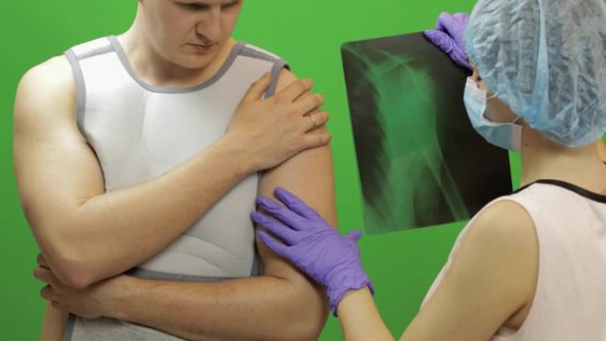 肩膀受伤的人。护士检查x光。固定肩部的绷带
