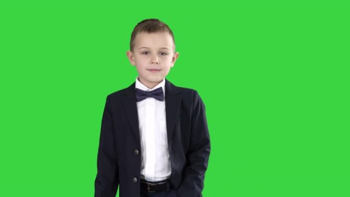 穿着正式服装的男孩在绿色屏幕上的口袋里走路，色键