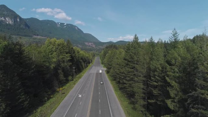 华盛顿州金条附近山区之间森林中繁忙的2号高速公路的鸟瞰图。无人机视频与上升的摄像机运动。