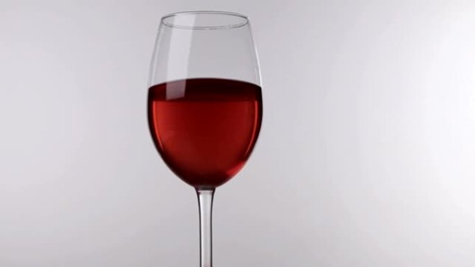 红酒在玻璃上的运动站在白色背景上，特写镜头。