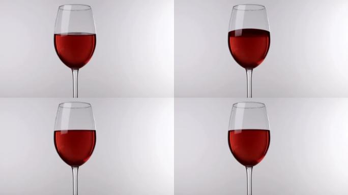 红酒在玻璃上的运动站在白色背景上，特写镜头。