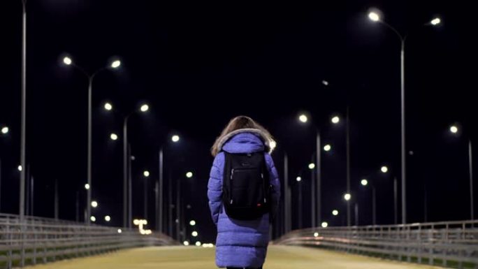 一个穿着冬季夹克的女孩走过一个荒凉的夜城