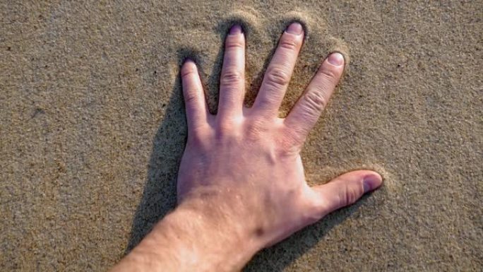 成年男性手在日落时在沙滩上留下手印慢动作