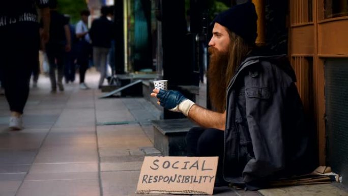 无家可归的人具有 “socail责任” 纸板，并在拥挤的街道上乞讨