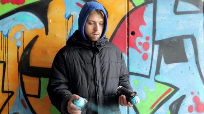 年轻的成年男子在涂鸦墙前摇晃喷雾瓶