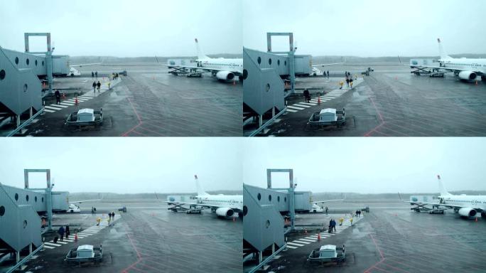 恶劣天气日: 乘客从机场航站楼步行到飞机登机楼梯。在国际机场登机