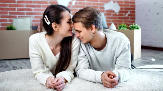 微笑的年轻夫妇享受爱情有温柔的感觉躺在地板上看着相机