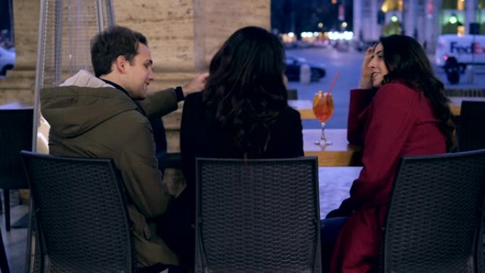 男人在亲吻坐在咖啡馆的女友时与朋友调情