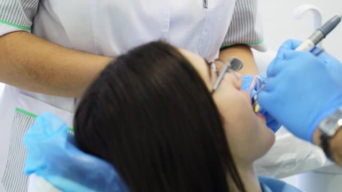 牙医正在钻年轻女性病人的牙齿。