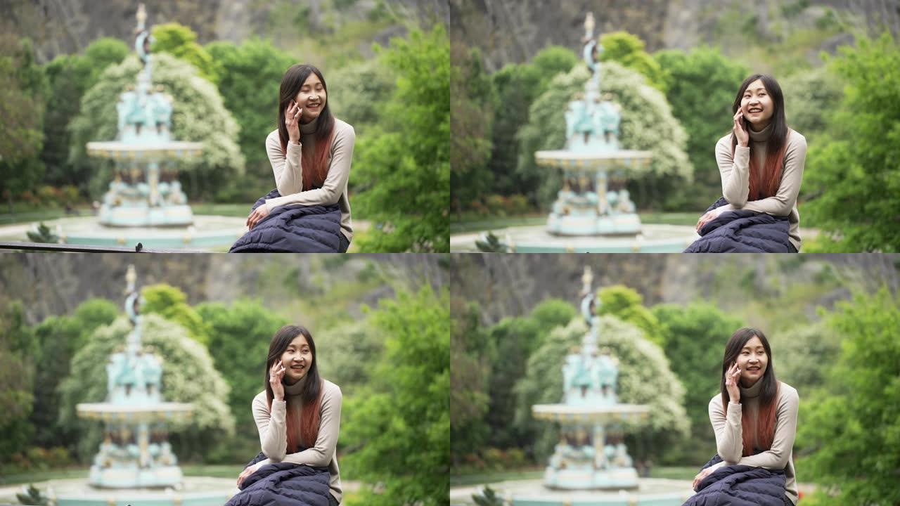 美丽的亚洲女人微笑着说话坐在公园里