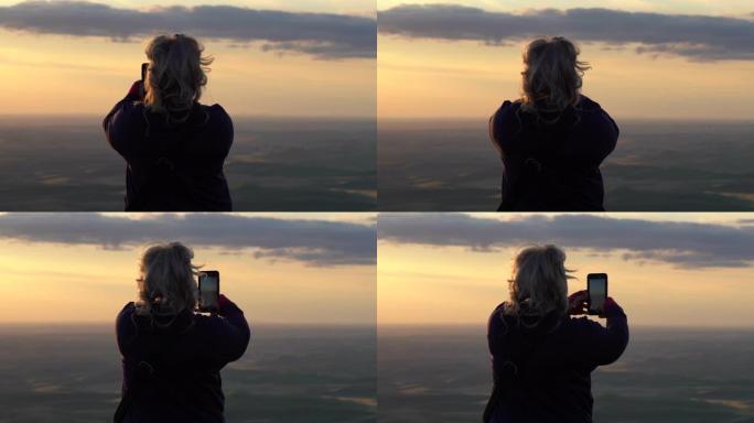 在华盛顿州帕卢斯地区日落时，金发女子用智能手机拍摄了一张全景照片。