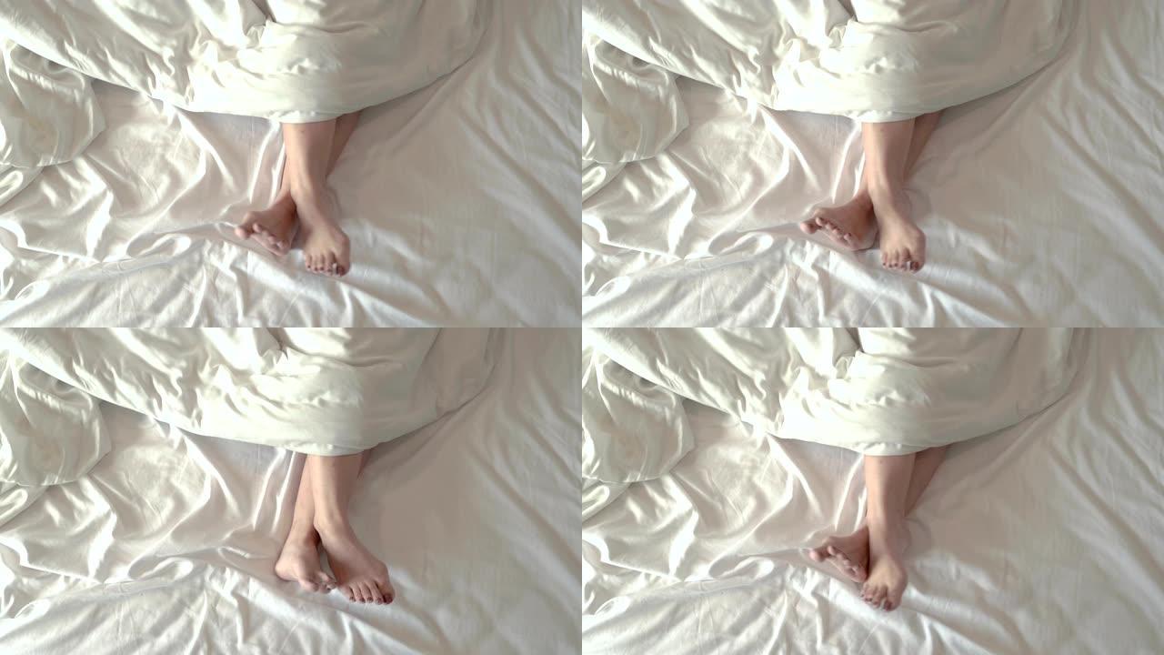 女孩的腿在白色的床垫上舒服地移动着