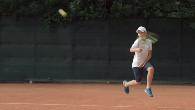 打网球，坚定的运动员少年专注于比赛，在红色的场地上拍球