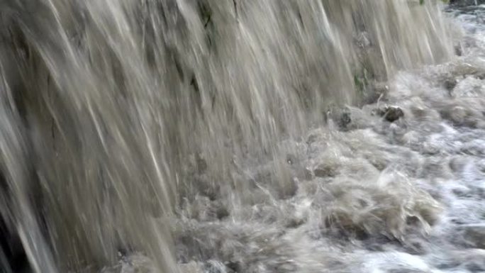 极度接近浑浊的冒泡水涌入河中。小瀑布。特写。4K。