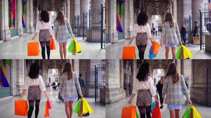 商场里两个带着购物袋的走路女人的后视图。漂亮女孩购物狂。4K (UHD