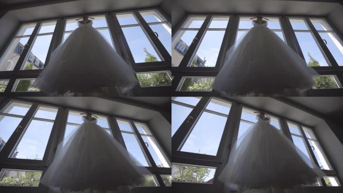 新娘的礼服挂在窗户上。非常漂亮和优雅。婚礼股票视频