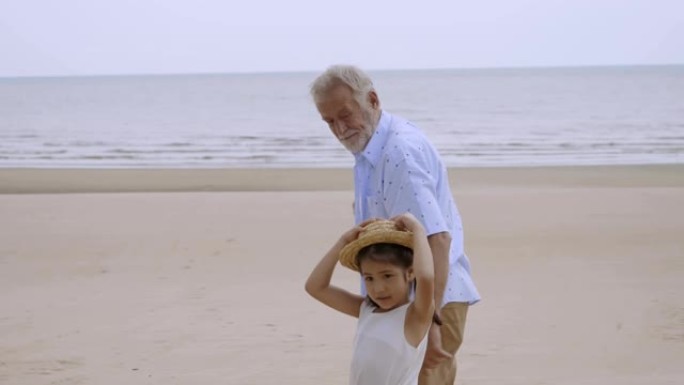 肖像老年老人手边展示魔法亚洲小女孩走在海滩上