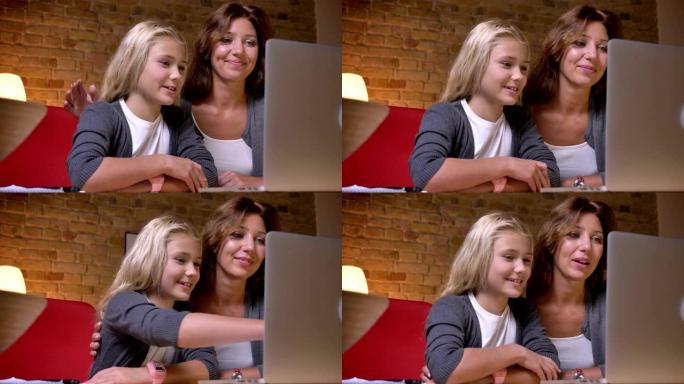 年轻母亲和女儿一起在笔记本电脑上看电影并讨论情节的特写肖像