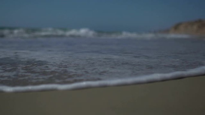 低角度视角和慢动作拍摄海浪和海泡海岸。