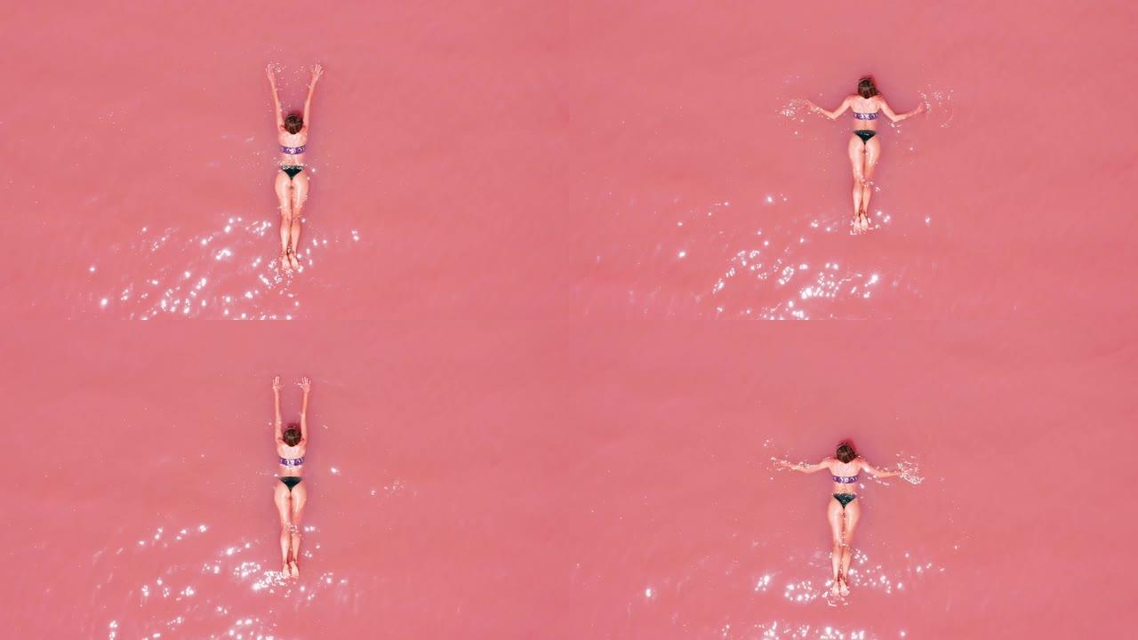 鸟瞰图。一个美丽的年轻女孩躺在粉红色的湖上，比基尼，太阳镜，粉红色的清澈的水，俯视图。概念: 海上空