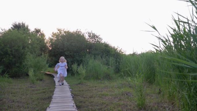 快乐的小朋友女孩和男孩在绿色植被中玩耍追赶并在大自然的木桥上奔跑