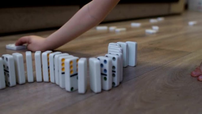 小男孩在房子的地板上玩多米诺骨牌。多米诺骨牌原则。