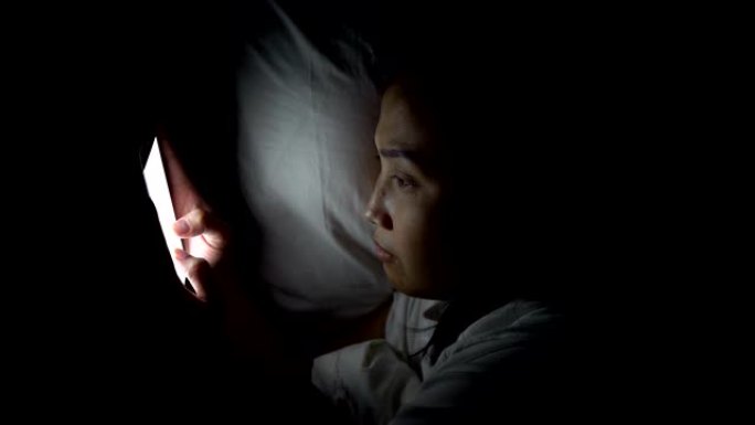 女人晚上在床上用智能手机玩游戏