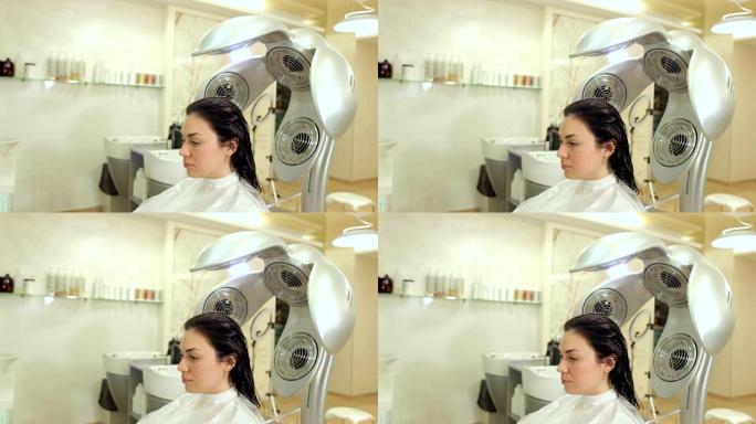 专业吹风机的特写镜头在美容院干燥年轻女孩的头发。
