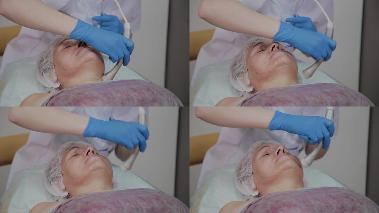 专业美容师在美容办公室为一名有微电流的老年妇女执行手术