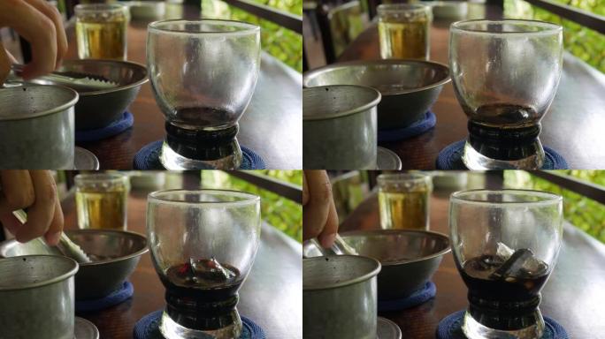 顾客在饮用前将冰放入黑咖啡中。在咖啡馆使用越南传统的phin过滤器。Ca phe den da。特写