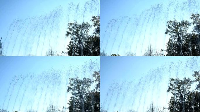 水从城市喷泉喷出，落在蓝天和日落的映衬下。特写。底视图。4K。