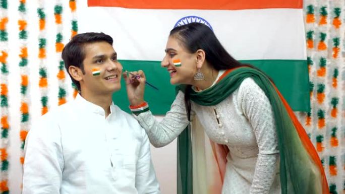 印度女孩在小男孩的脸上画了一面国旗-国旗。独立日概念