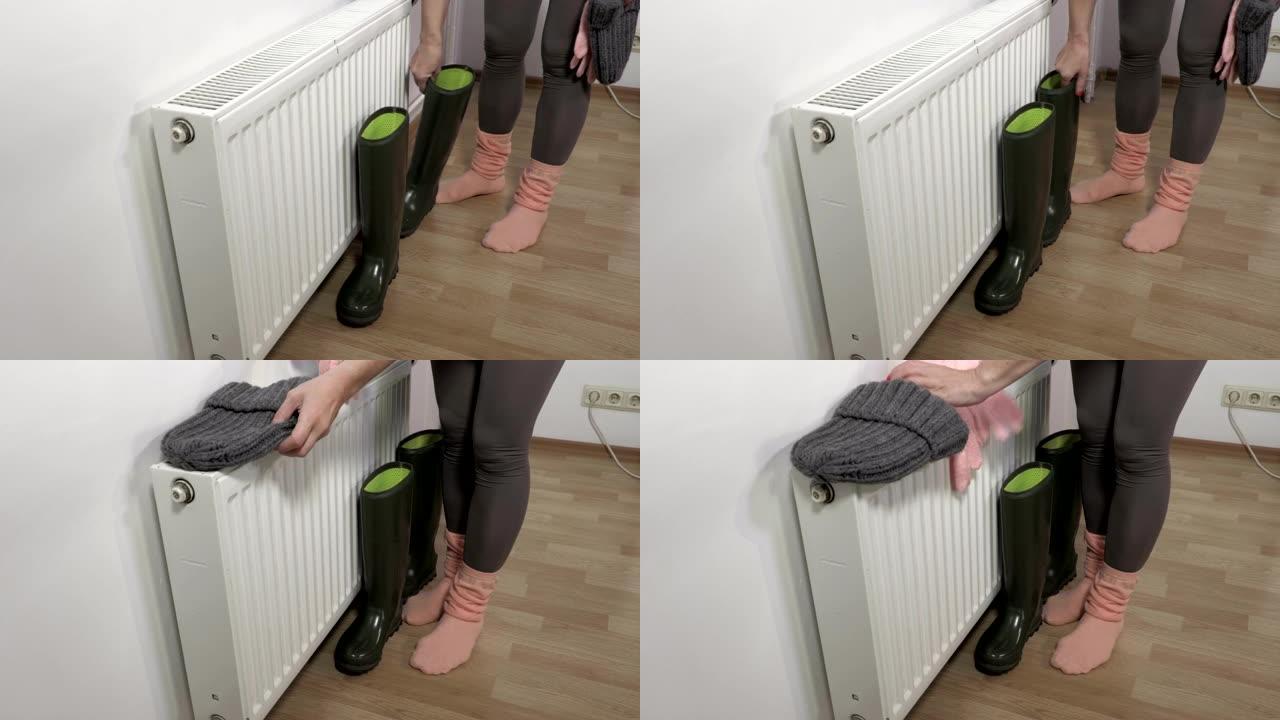 女人把靴子和衣服放在暖气散热器附近晾干