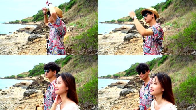 4k中拍摄的年轻成年亚洲夫妇男女旅行旅游，在热带岛屿的岩石海岸散步和站立，在暑假里面带微笑地看着对方