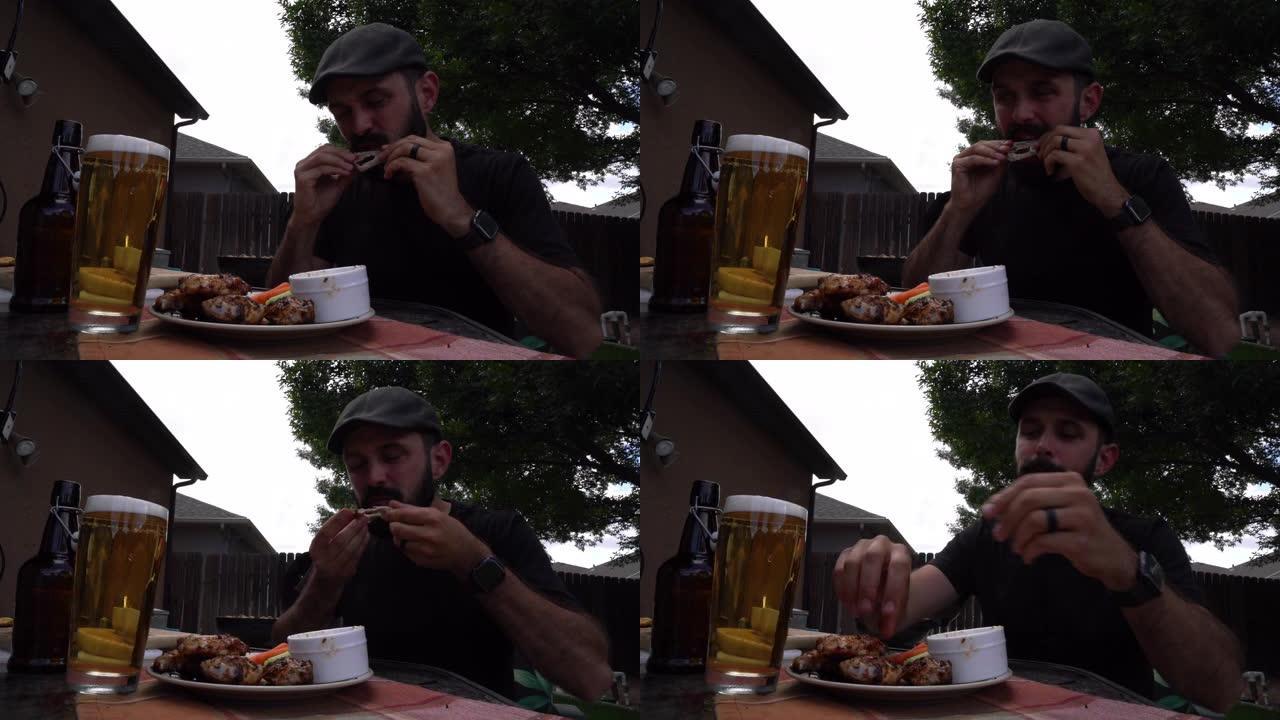 三十多岁的年轻人在夏天的时候喝啤酒，在后院的桌子上吃辛辣的水牛鸡翅