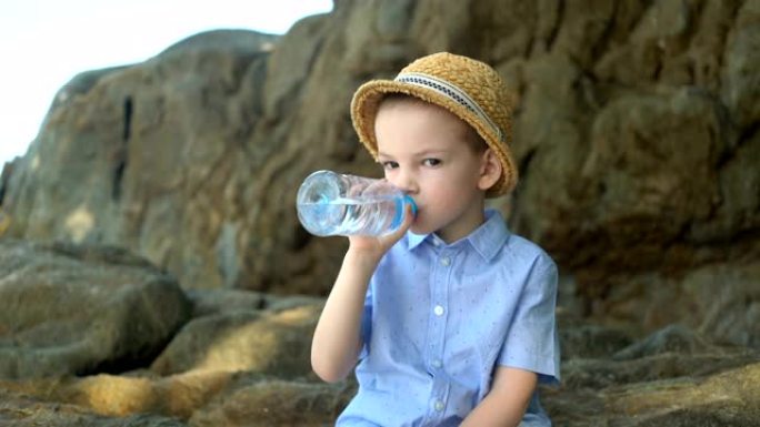 英俊可爱的男孩在晴天喝塑料瓶中的清水