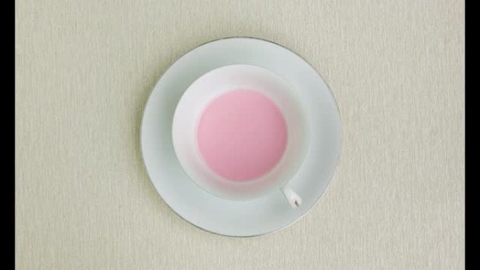 将草莓牛奶添加到棕色背景的白色杯子中