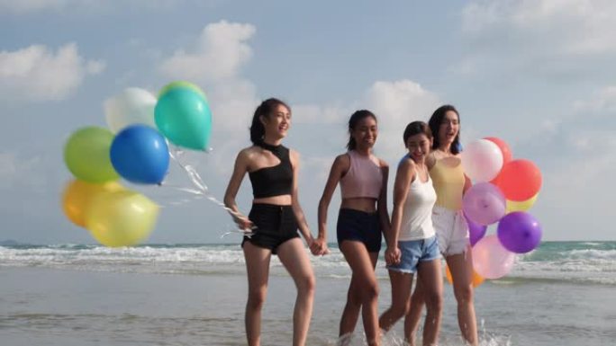 亚洲女子组合带着气球一起在海边海滩散步。青年亚洲快乐情感和周年庆典。4k分辨率和慢动作。