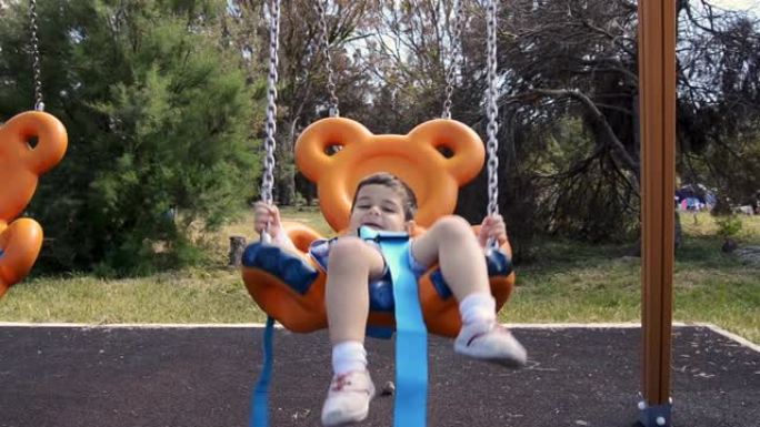 两岁男孩在公园的泰迪熊形秋千上放松