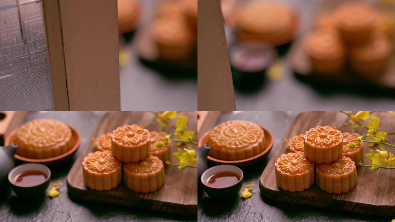 美丽的月饼在木托盘与茶和花在黑石板背景。中国传统的中秋节观念。