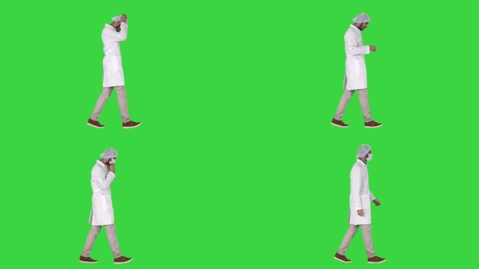 阿拉伯医生在绿色屏幕上行走并戴上医疗帽，色度键