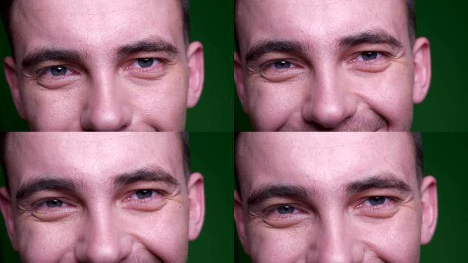 成人迷人男性脸的特写镜头，眼睛看着相机，微笑的面部表情，背景孤立在绿色上