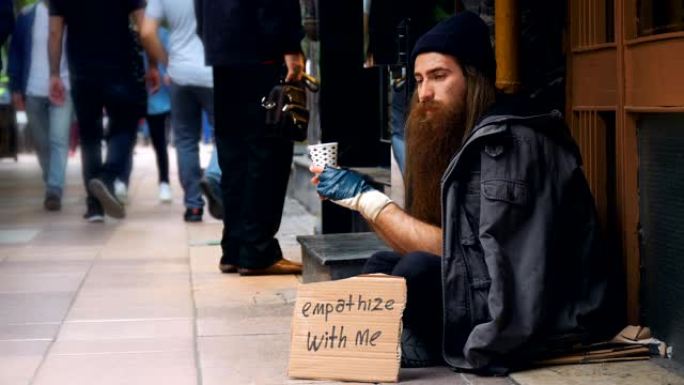 无家可归的人带着 “同情我” 的纸板，在拥挤的街道上乞讨