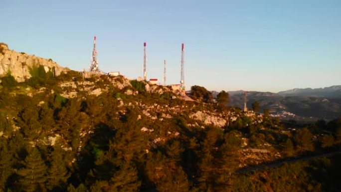西班牙阿利坎特滨海阿尔塔塞加里亚山日落时电信天线的空中无人机视图