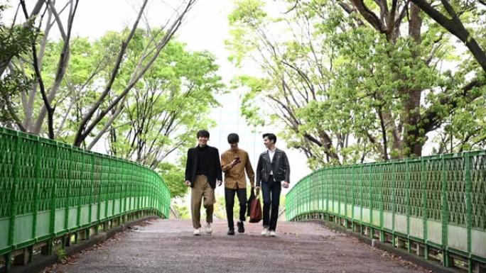 三个年轻的男性朋友一起穿过公园聊天