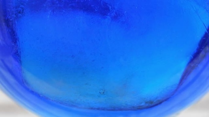 蓝色橙色风味利口酒与玻璃杯中的冰块反应