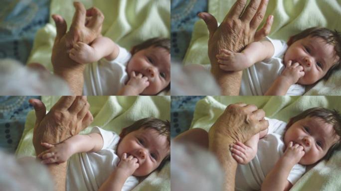 婴儿用爷爷的手玩耍的美丽慢动作